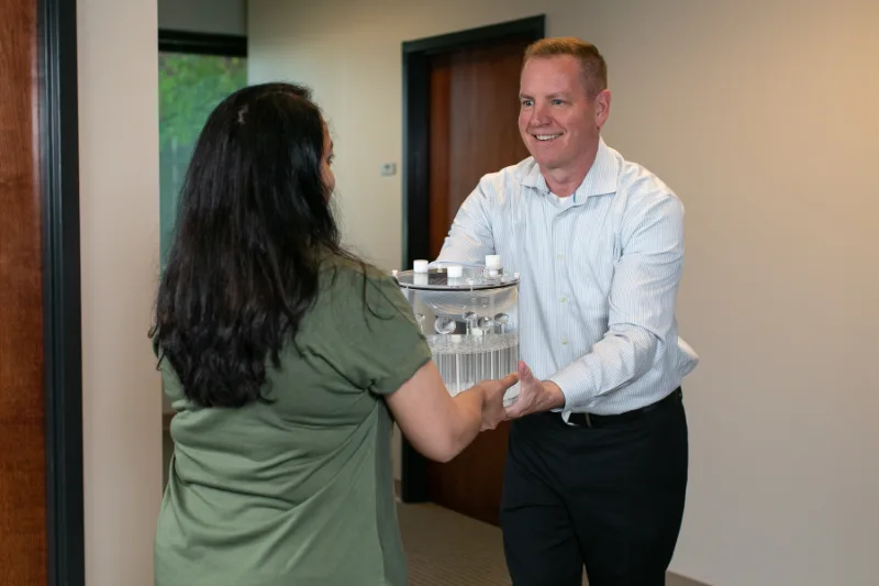 RadiologicalPhysicsAssociates-3137 RPA team member handing a clear acrylic test phantom to a colleague